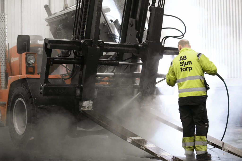 Workers cleaning a truck with high-pressure system – Tangen sustainability in transport.